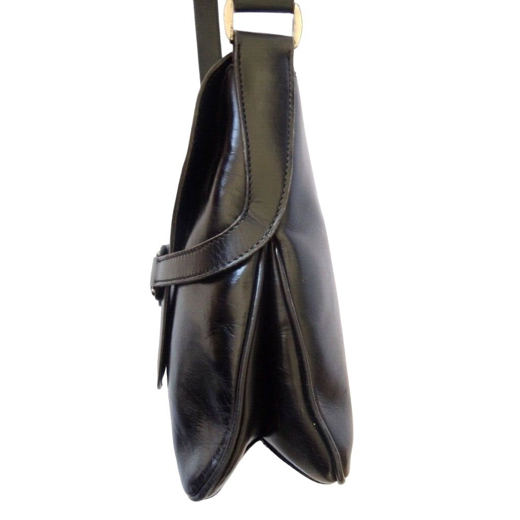 1970s Gucci saddle bag in black leather with muted gold hardware, an expandable bottom, wide shoulder strap, and burgundy leather lining