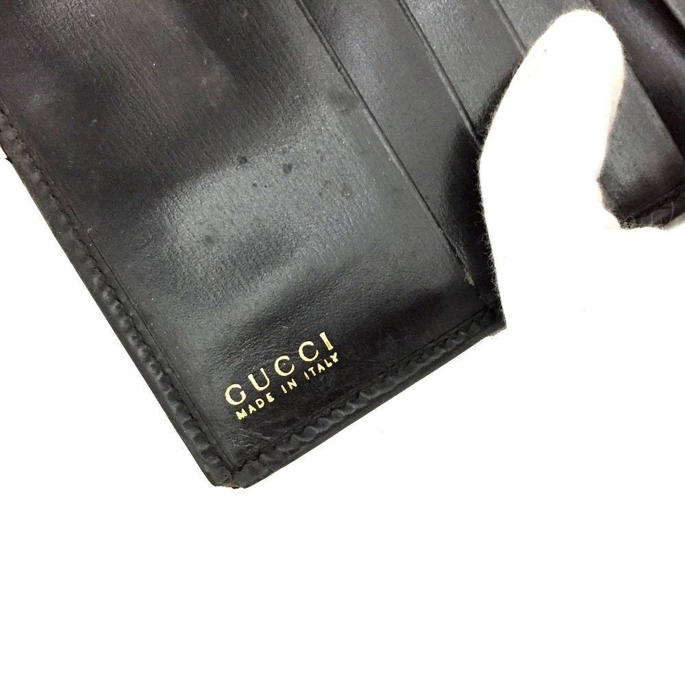 Gucci, blsck glossy leather, bi-fold style, rectangular, wallet with multiple pockets, tons of card slots, and a gold, hinged G clasp