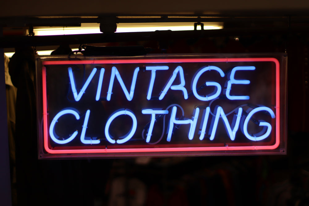 Neon sign that reads "Vintage Clothing" in blue with red rectangle border around words