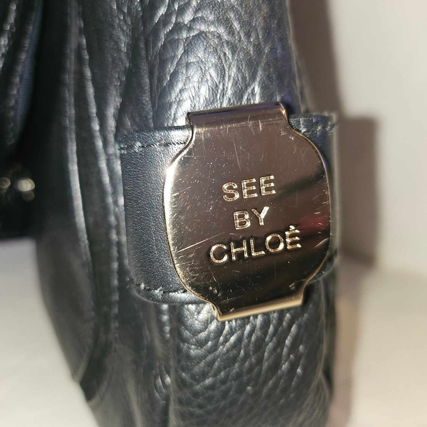 See By Chloe black pebbled leather saddle bag with two leather flowers