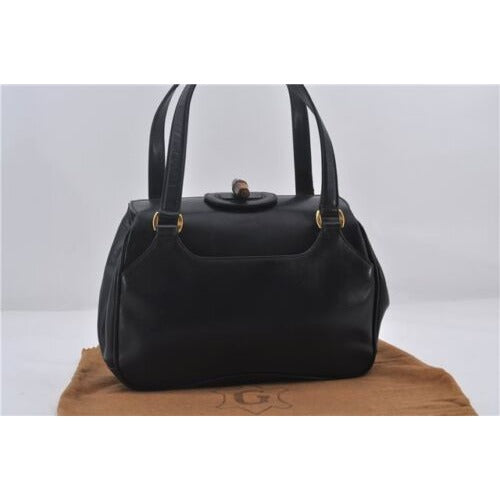 Mod Gucci, black leather shoulder bag with two longer straps, two exterior pockets, a hinged opening, and a gold and bamboo accent clasp
