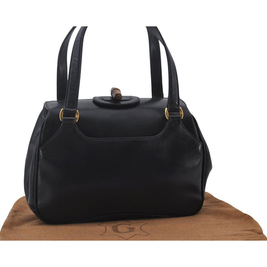 Mod Gucci, black leather shoulder bag with two longer straps, two exterior pockets, a hinged opening, and a gold and bamboo accent clasp